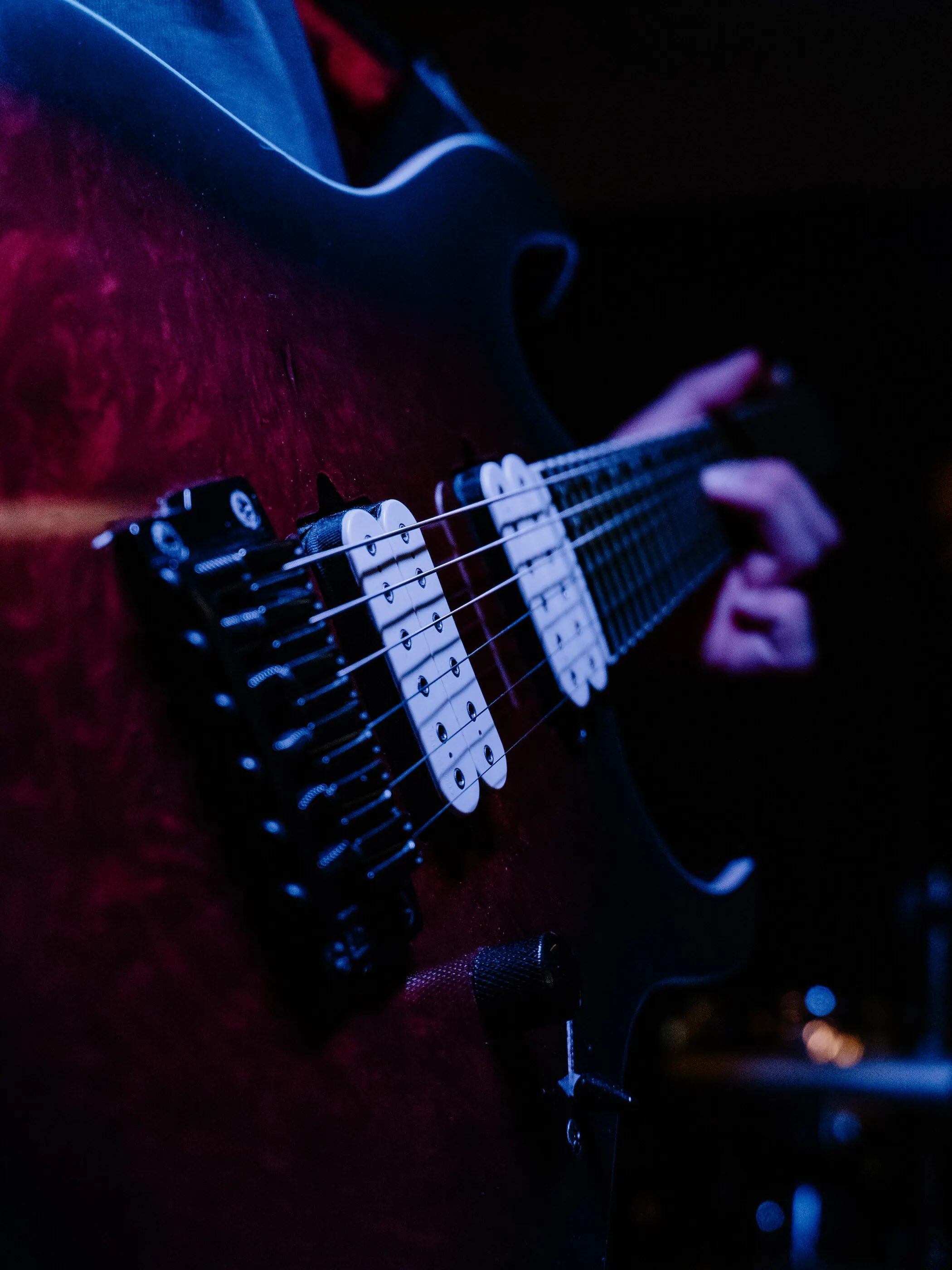Nahaufnahme einer E-Gitarre im roten und blauen Bühnenlicht