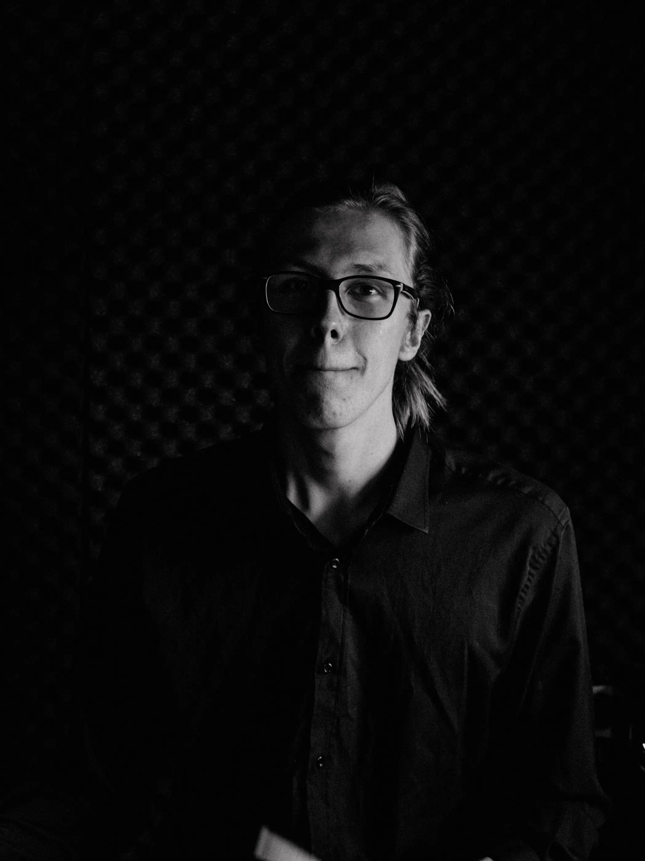 Schwarz-Weiß-Portrait eines Mannes mit Brille vor dunklem Hintergrund
